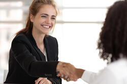 Smiling business job candidate shaking hands with another woman at a job interview