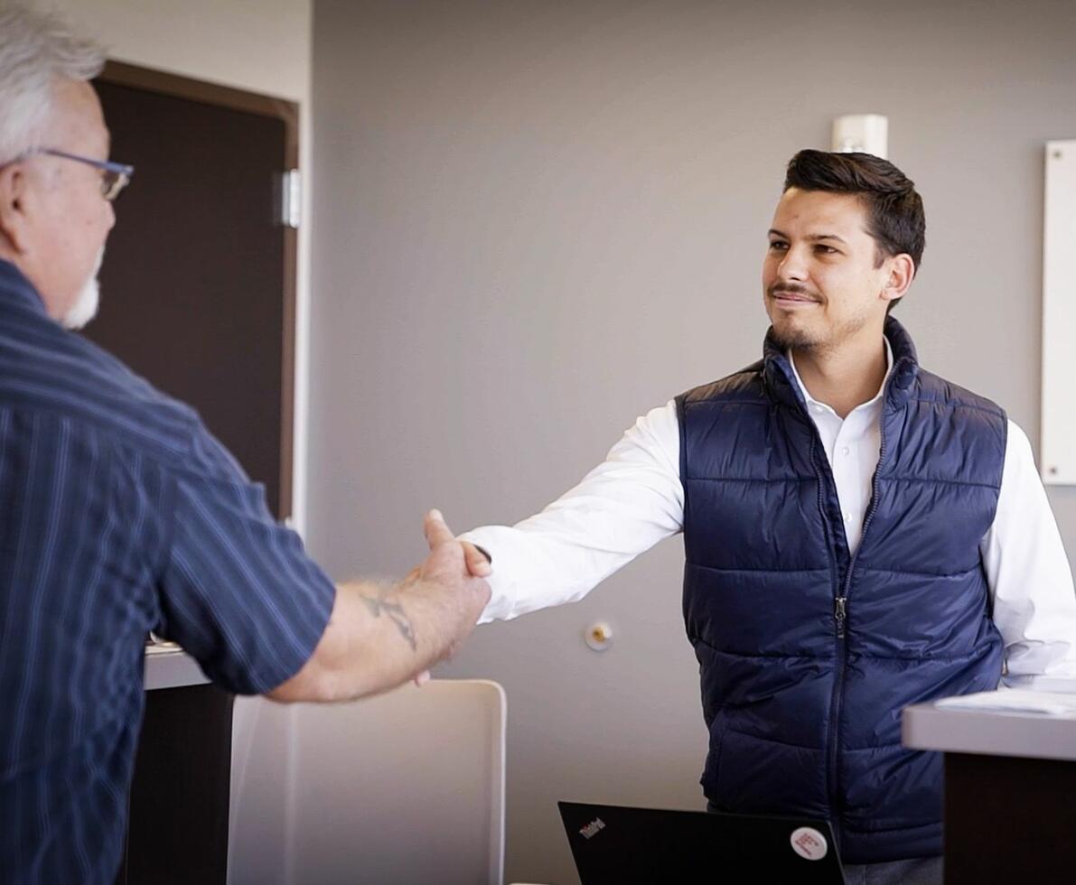 A receptionist in a Spherion office shakes the hand of an older gentleman candidate