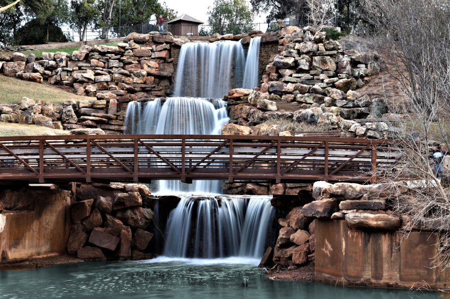 Four tier water fall surrounded by rocks with walking bridge in Wichita Falls Texas