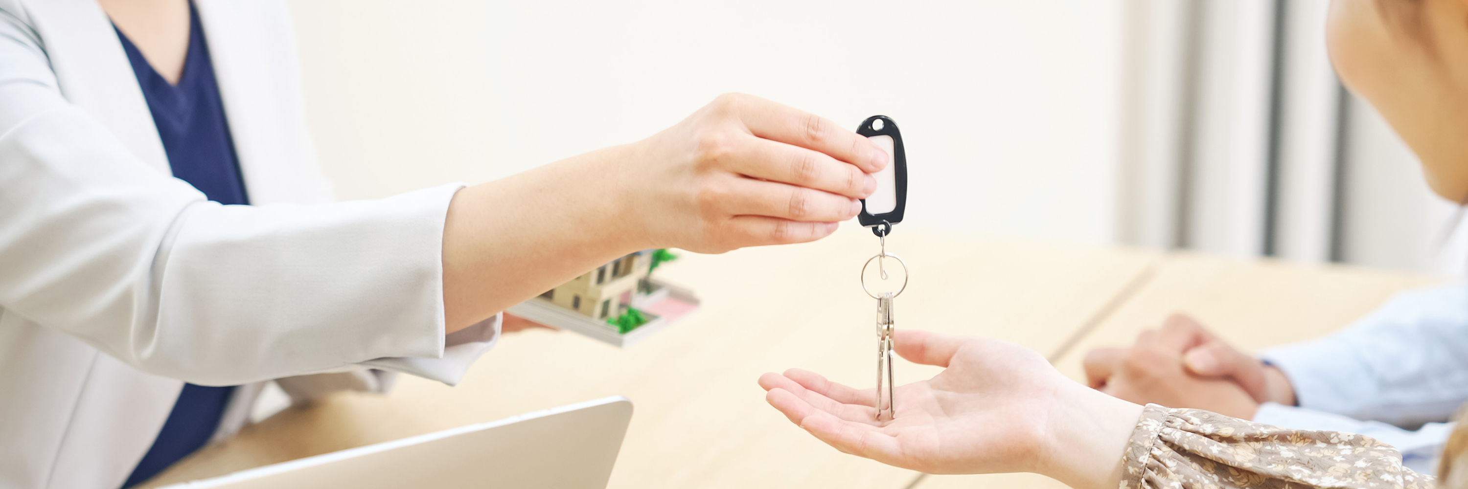 Close-up of a woman handing keys to a couple