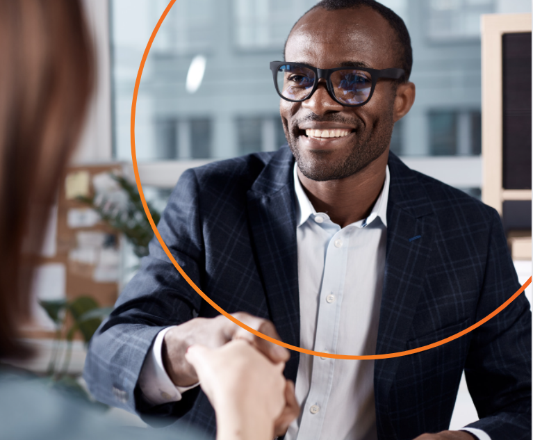 African-American Male in a suit and wearing glasses smiling and shaking hands wtih a woman