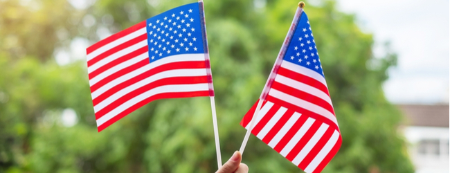 Two American flags held up against a green background