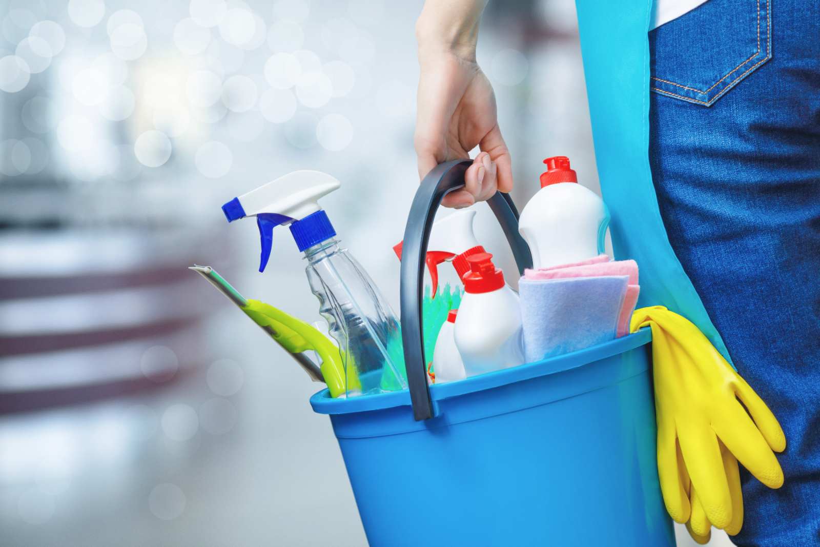 Person_holding_a_blue_cleaning_bucket_full_of_housekeeping_supplies.