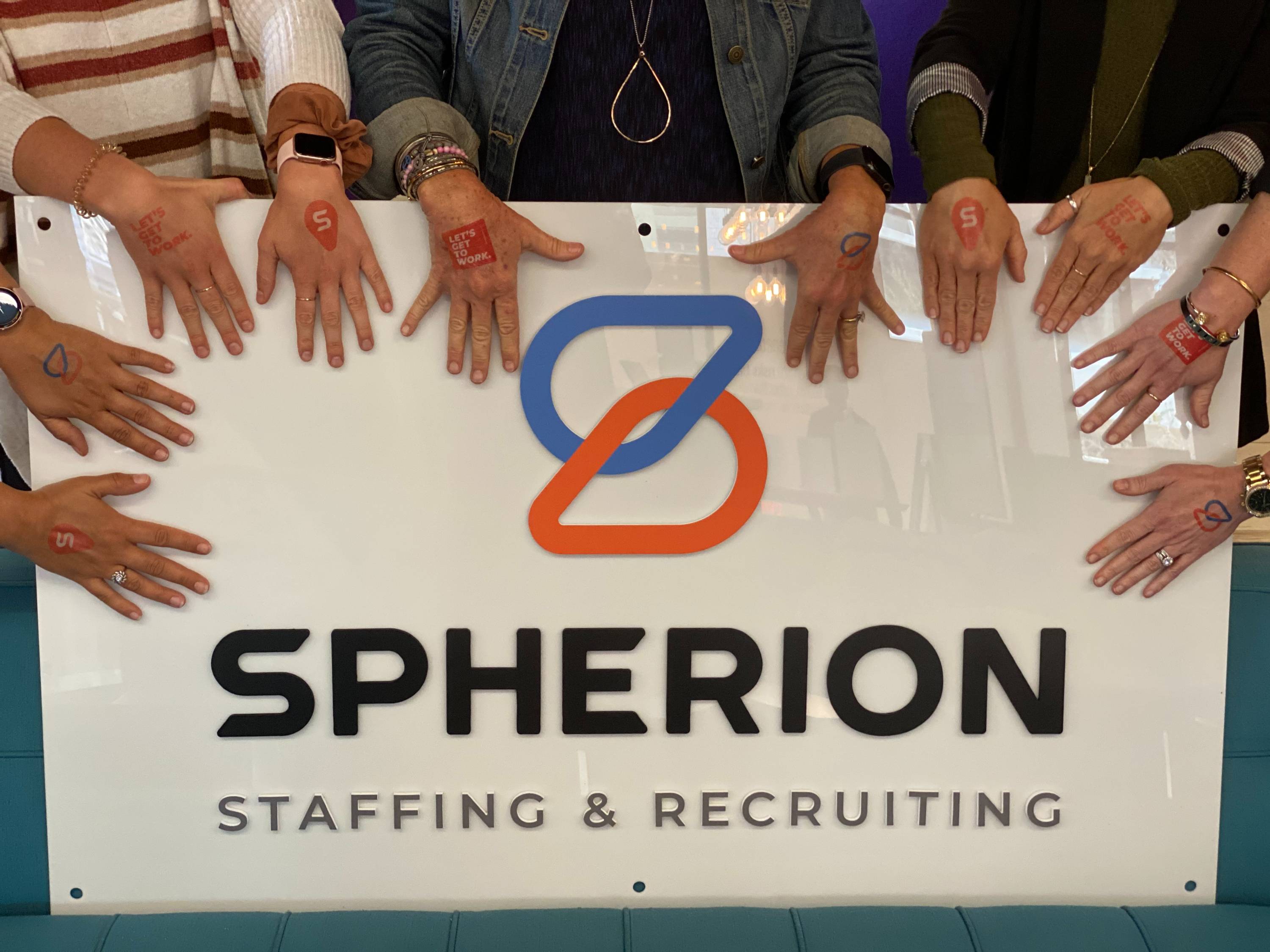 Hands surrounding a white Spherion logo sign