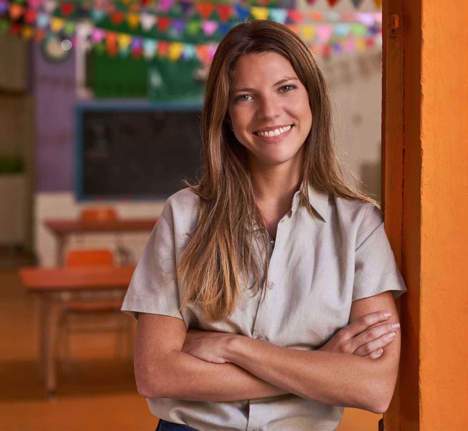 Daycare teacher smiling with arms crossed in her classroom