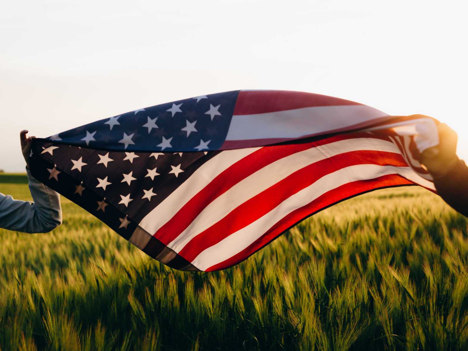 American Flag waving in a field at sunset