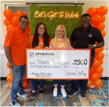 The Spherion Fort Myers team poses with National Staffing Week winner Niurka Rodriguez in front of a backdrop and balloons