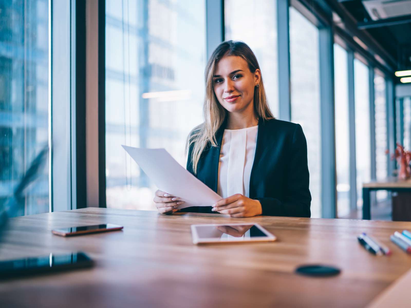 Woman in a suit in an office setting researching franchises and smiling at the camera