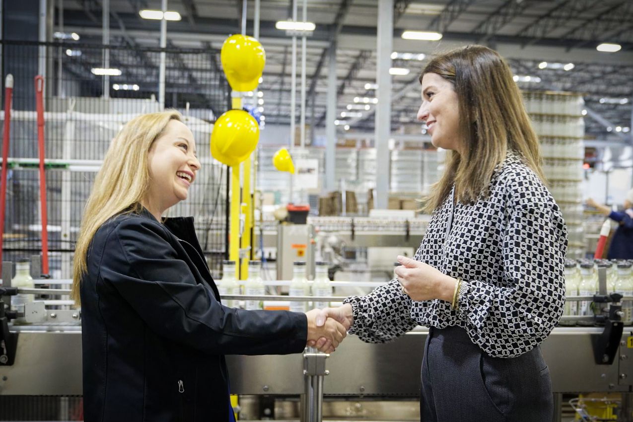 Two women shaking hands in a factory setting