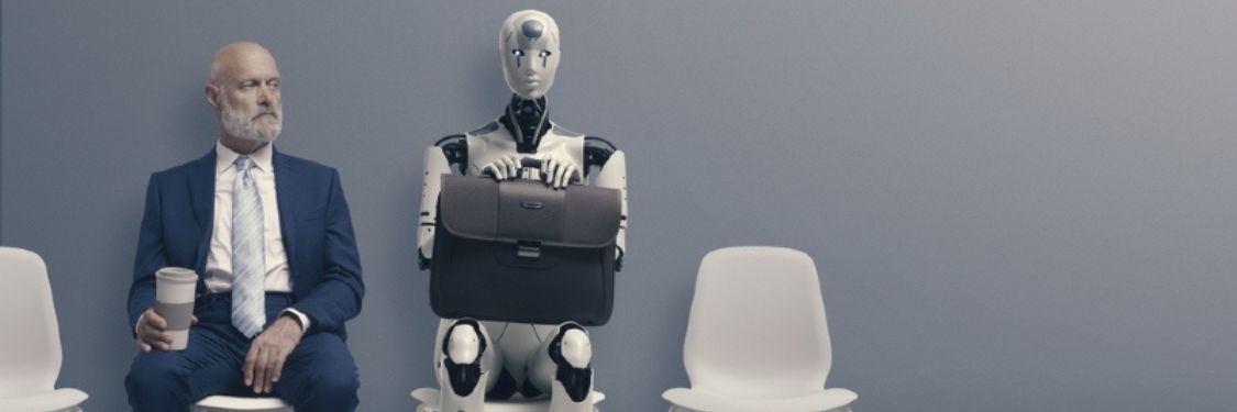 Seated man in a suit looking at a seated robot holding a gray briefcase on a gray background