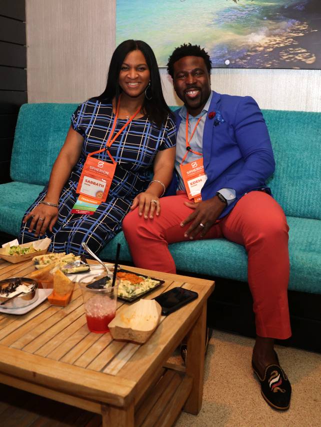 A young couple smiling and sitting on a teal couch