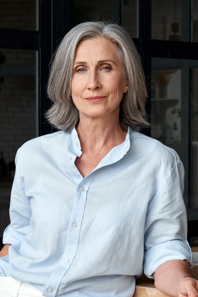 A woman in a light blue blouse with gray hair in an office setting