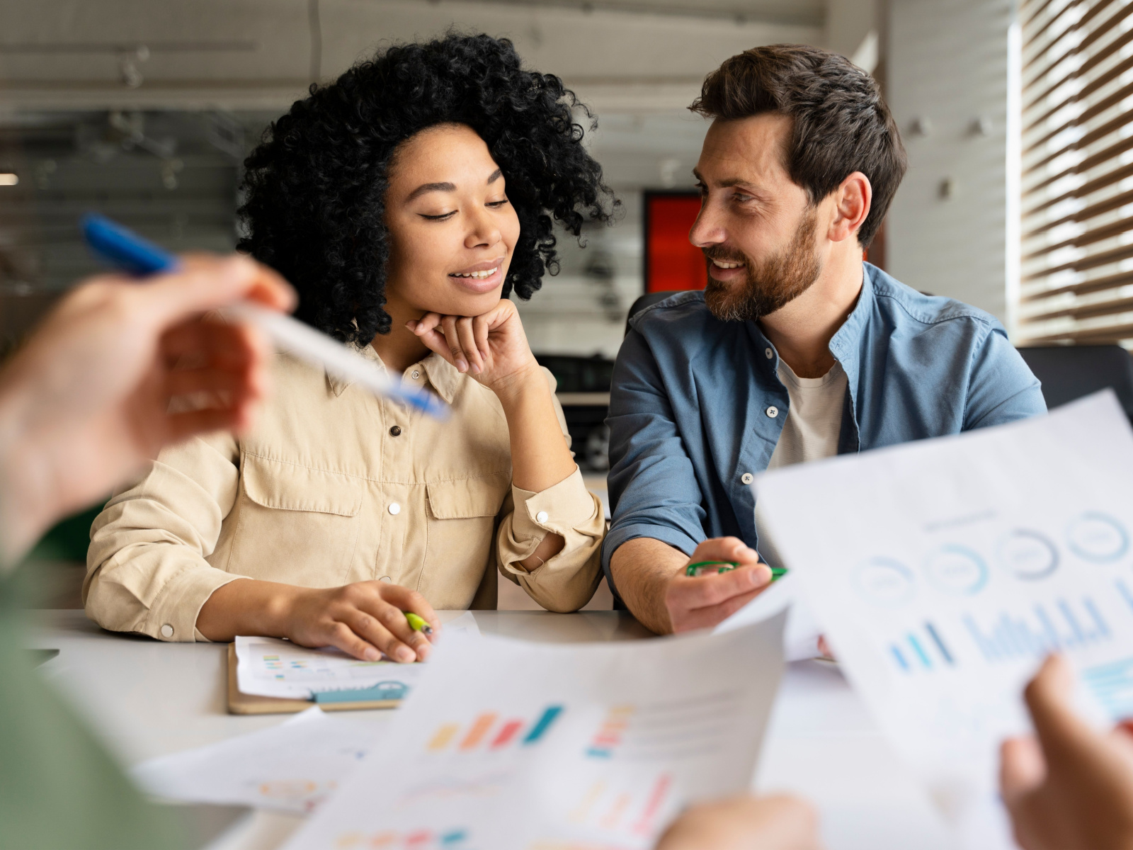 African-American Woman and Caucasian Man smiling together while looking over business documents