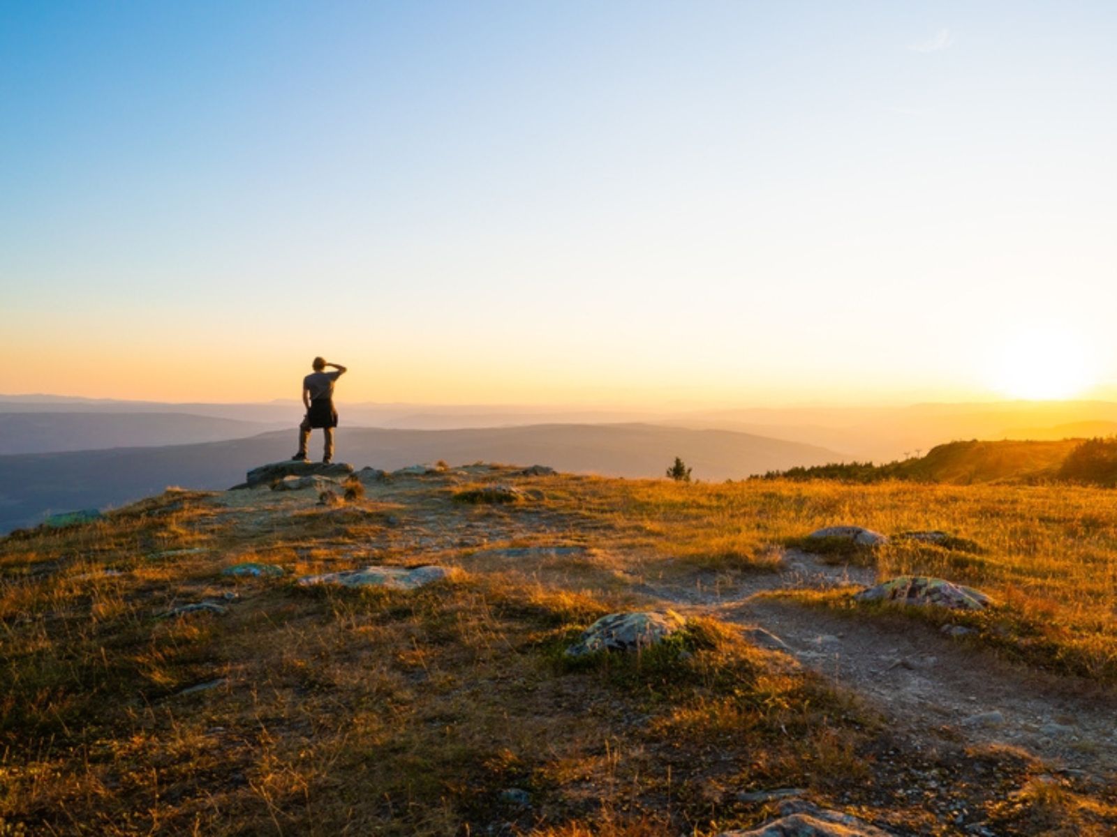 Person looking out over a mountain vista at sunrise