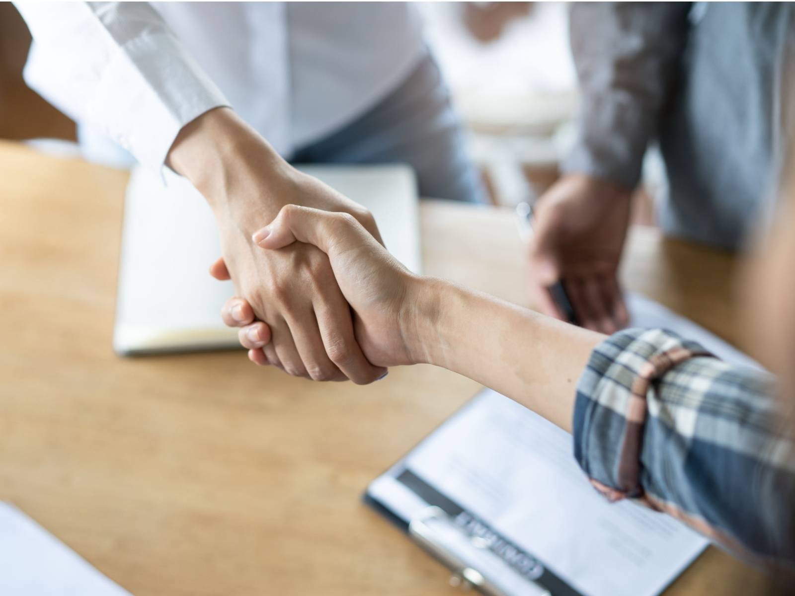 Overhead view of two people shaking hands over a table with documents on it