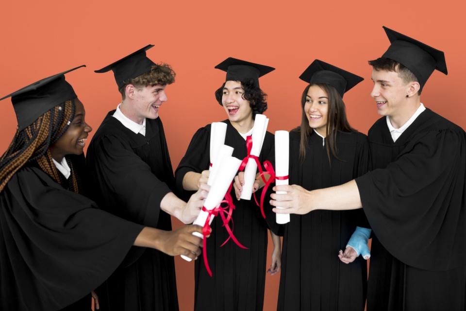 Diverse group of students holding diplomas