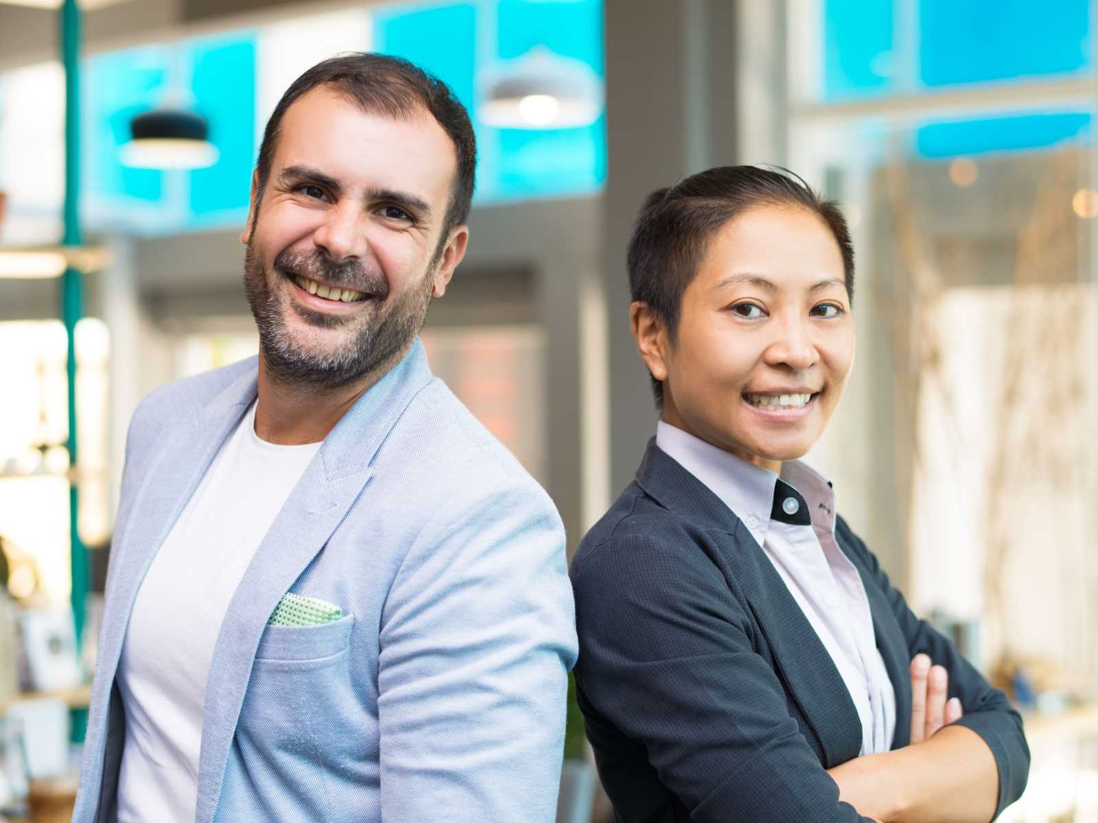 A man and woman standing back to back and smiling