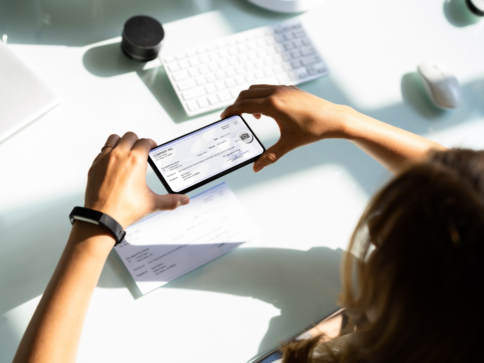 Overhead view of a woman depositing a check by mobile phone