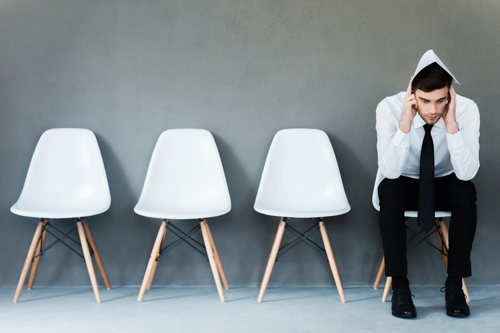 Man waiting for interview with resume on head