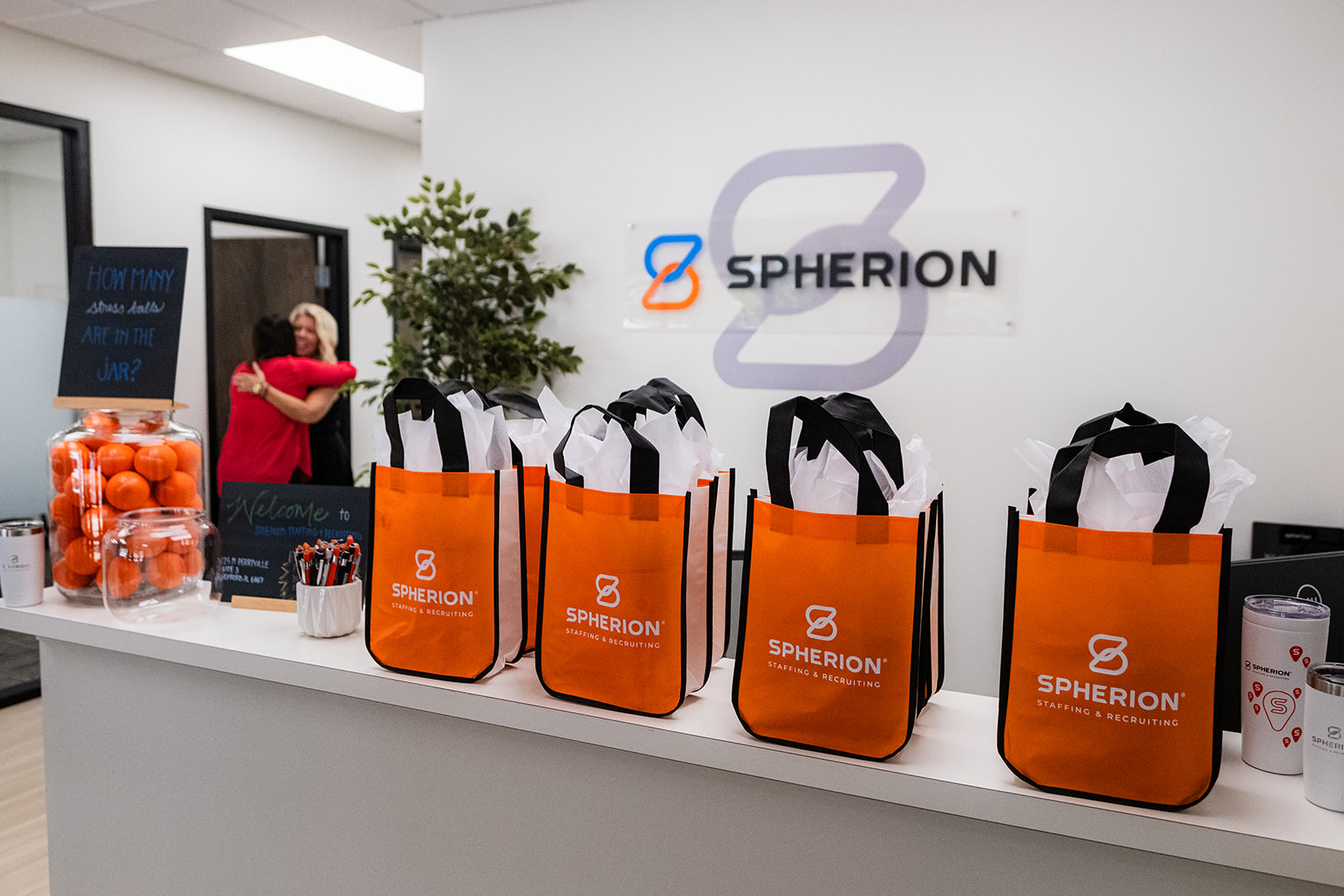 Orange shopping bags line a receptin desk. The plaque on the wall behind them reads, "Spherion Staffing & Recruiting."