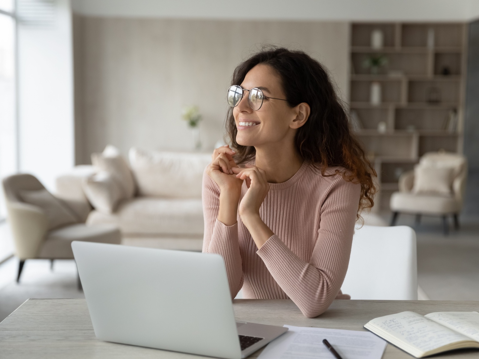 Young woman looking up optimistically from her desk