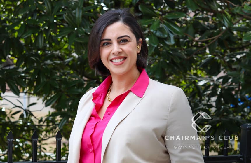 A photo of a woman in a business suit against a leafy backdrop