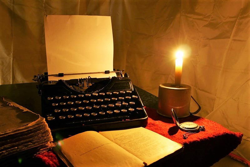 Manual typewriter, book and candle