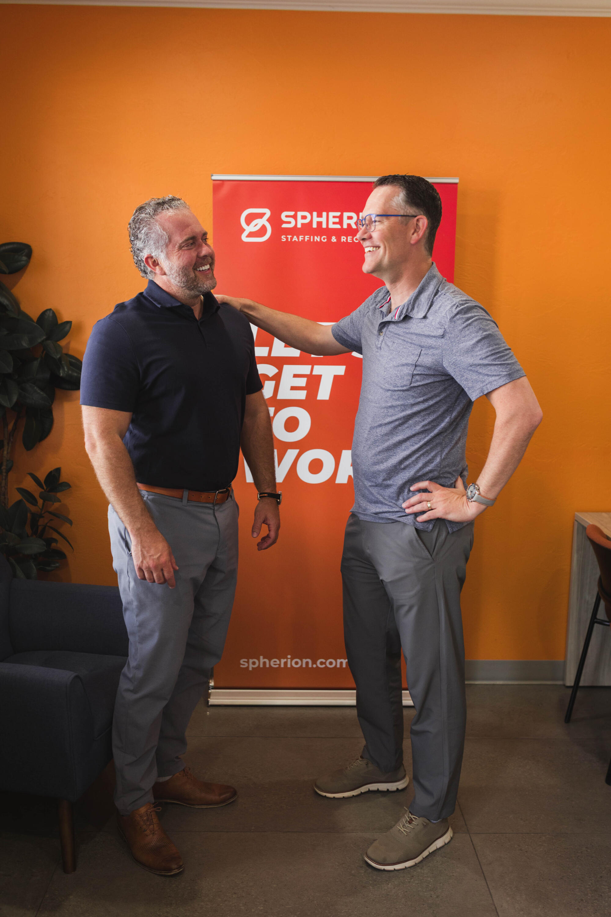 Two brothers posing in front of a Spherion sign