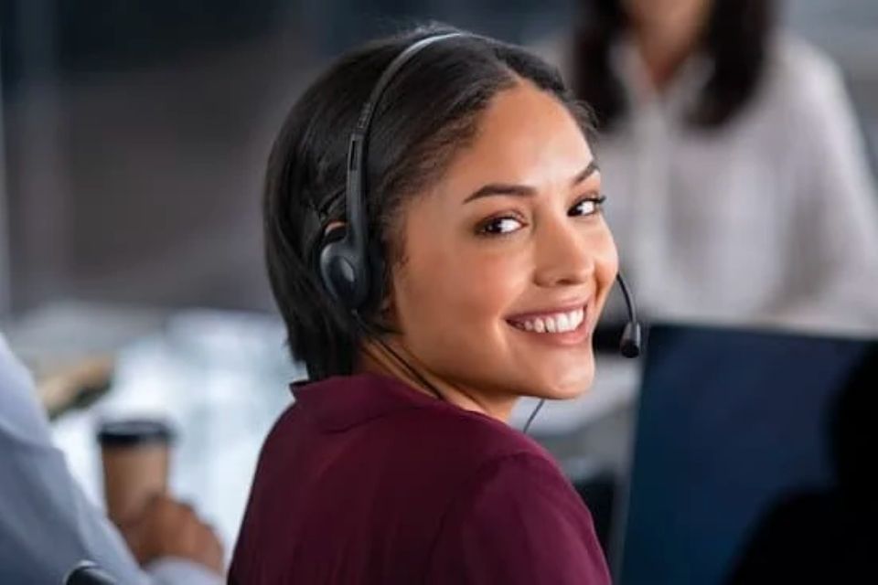 A woman wearing headphones smiling and looking backwards toward the camera