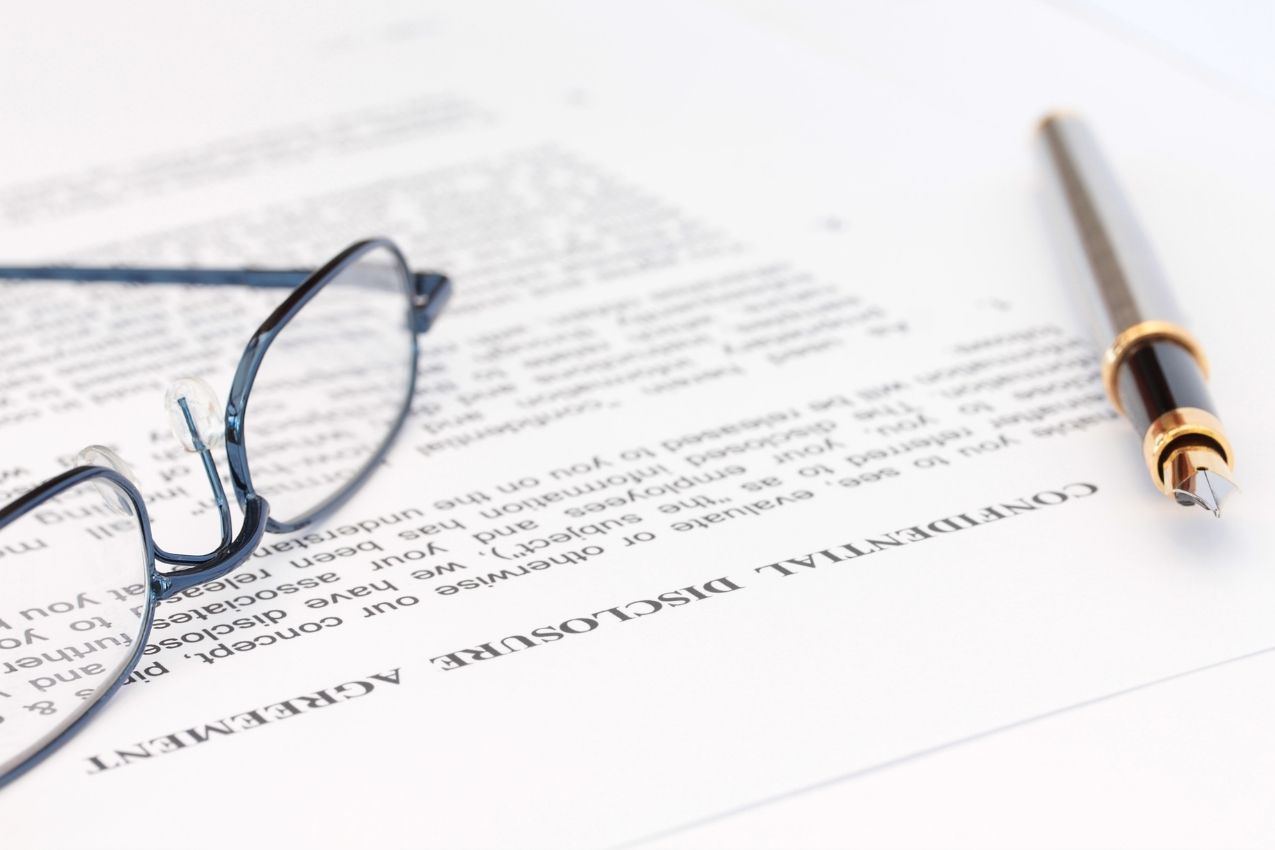Photo of a pair of glasses and a pen resting on a legal document
