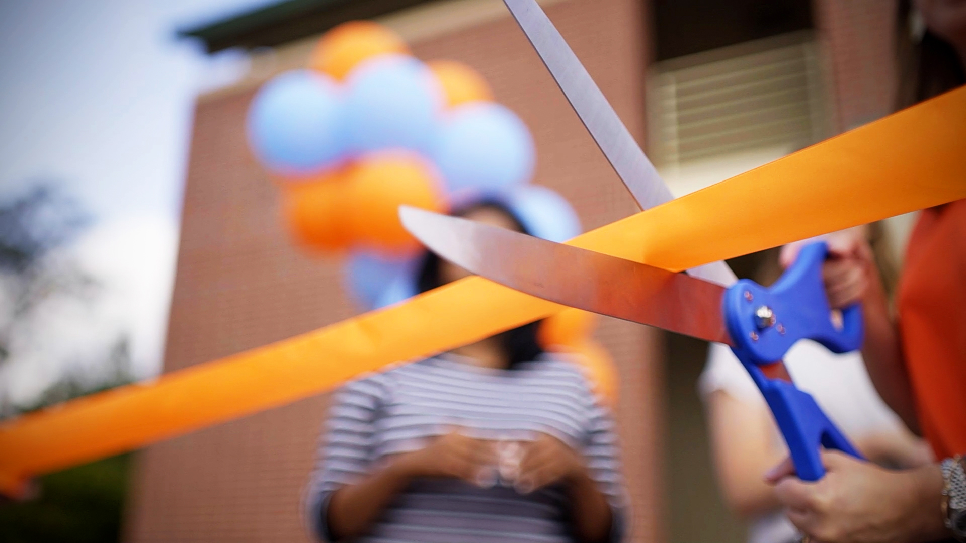 Compare and Understand the Best Franchise Model for You Closeup of a hand cutting an orange ribbon with blue scissors