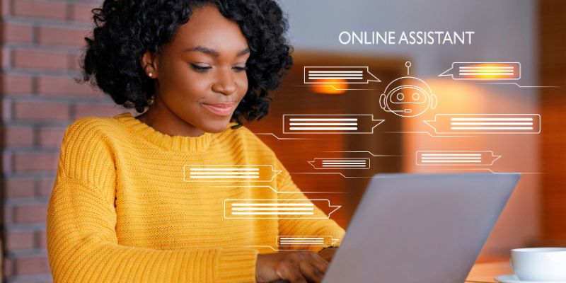 African-American woman in an orange sweater working on a laptop