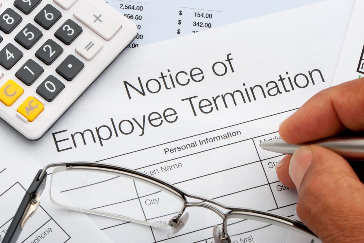 Close-up of a calculator, eyeglasses, and paper that reads, Notice of Employee termination