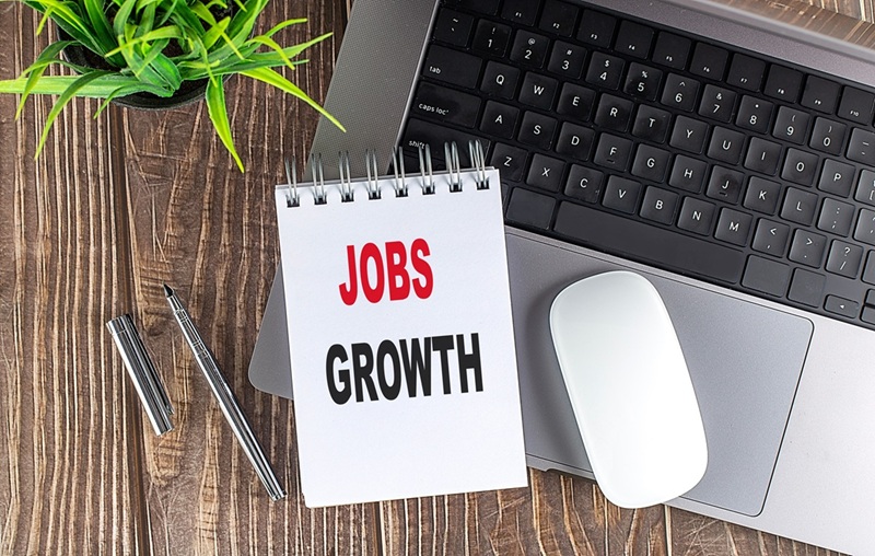 Jobs growth on notepad with laptop keyboard and mouse