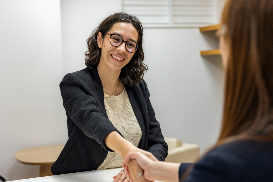 A female recruiter smiling and shaking hands with a job candidate