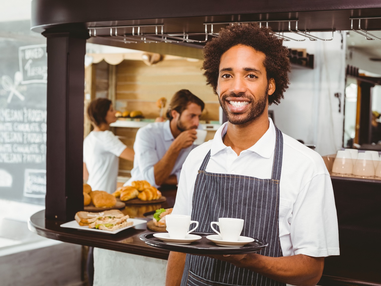 Server, young man smiling serving tray of coffee