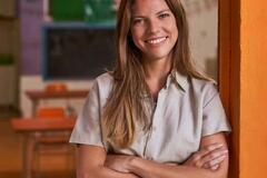 Daycare teacher smiling with arms crossed in her classroom