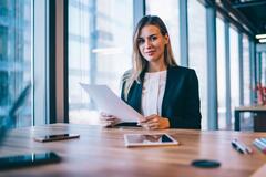 Woman in a suit in an office setting researching franchises and smiling at the camera