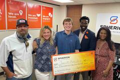 A group of people smiling and holding a giant orange and yellow check