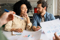 African-American Woman and Caucasian Man smiling together while looking over business documents