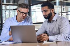 Two businessmen looking at a laptop in an office setting