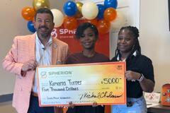 Three people smiling and holding a giant orange check