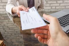 A businesswoman handing a paycheck across a desk