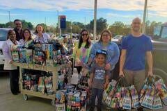 A group of people posing with donation bags in an outdoor parking lot