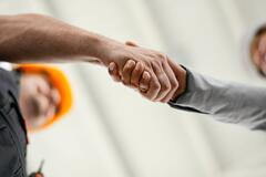 Close up of factory worker giving handshake to a engineer