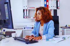 An African-American woman working on a computer in an office setting