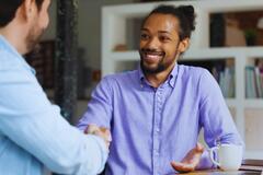 Two men shaking hands and smiling in an office setting