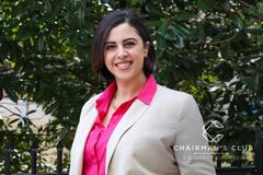 A photo of a woman in a business suit against a leafy backdrop