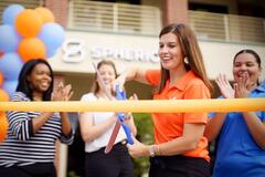 A woman cutting a ribbon at a Spherion office grand opening