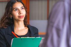 Woman holding a clipboard and interviewing a colleague
